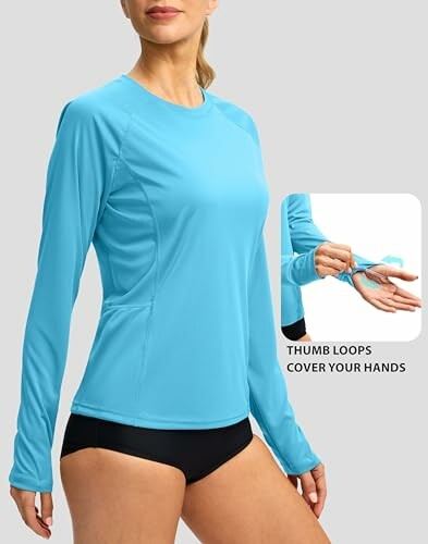 Woman wearing a blue long-sleeve rash guard with thumb loops.